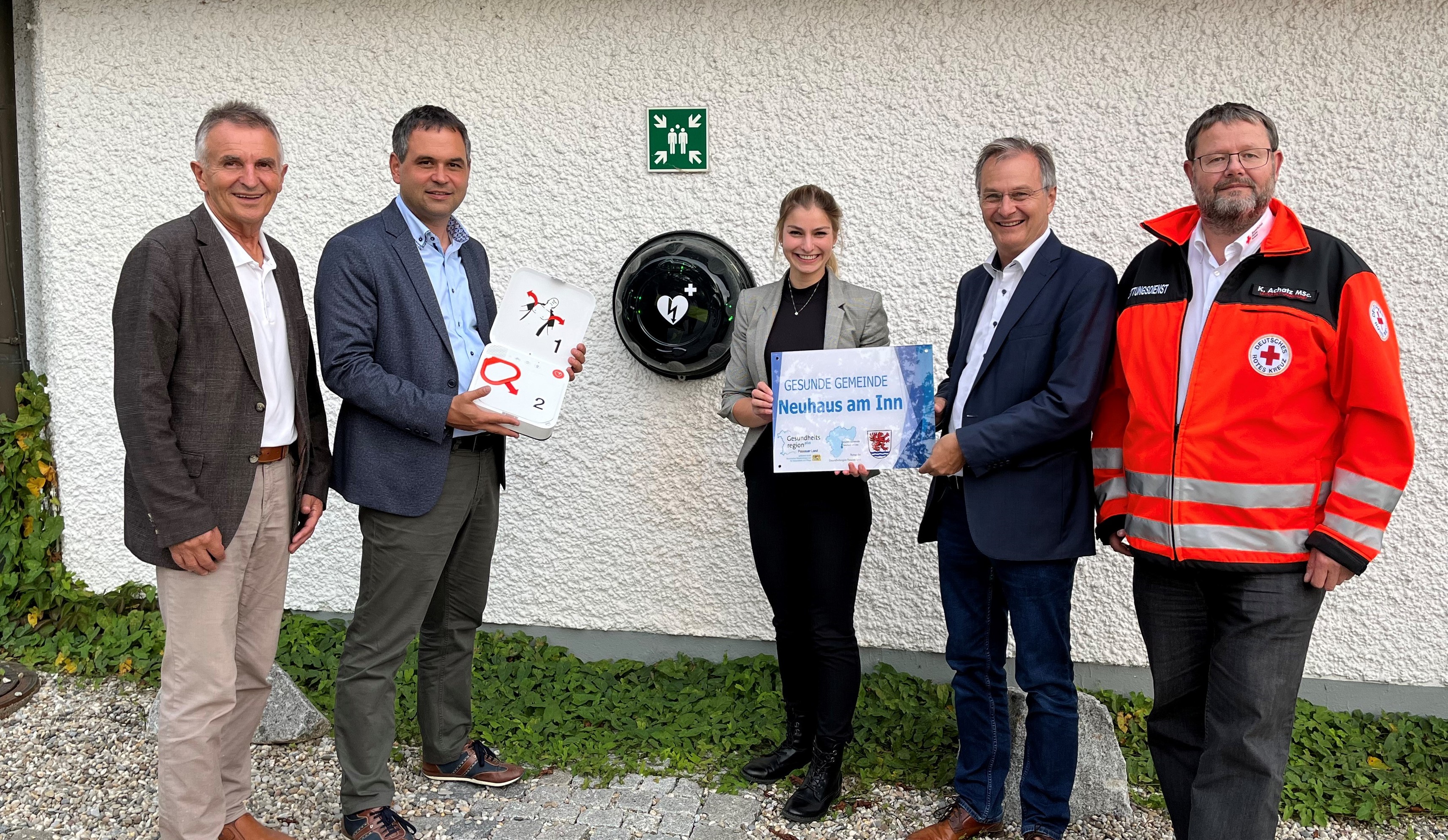 BRK-Kreisverbandsvorsitzender Walter Taubeneder (v.l.), Landrat Raimund Kneidinger, Lisa Fraunhofer (Geschäftsstellenleiterin GesundheitsregionPLUS Passauer Land, Bürgermeister Stephan Dorn und Klaus Achatz (Leiter Rettungsdienst und Beauftragter für Medizinproduktsicherheit beim BRK-Kreisverband Passau) am neuen AED-Standort in Neuhaus am Inn.