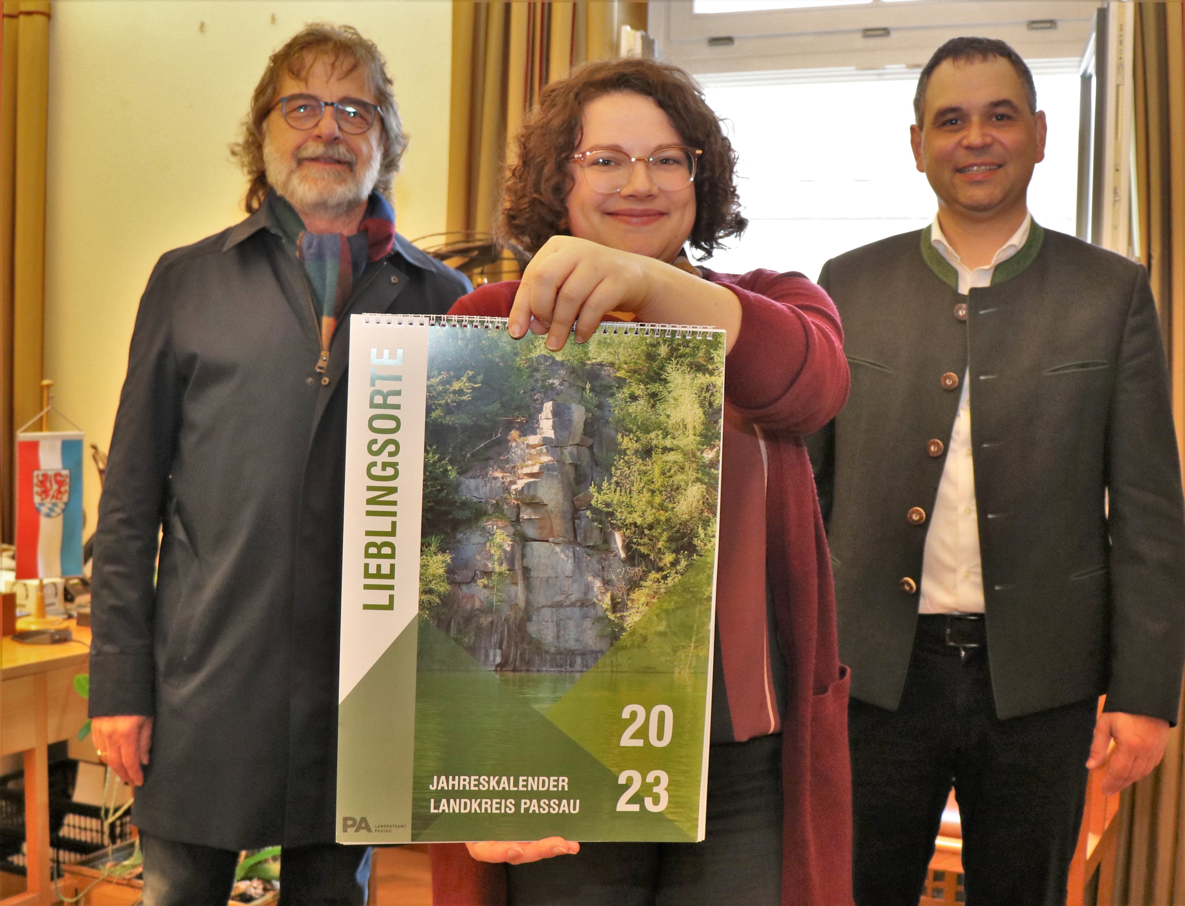 Julia Bösl-Sachse vom Kulturreferat präsentiert den Landkreis-Kalender 2023, zusammen mit Landrat Raimund Kneidinger (rechts) und Kulturreferent Christian Eberle