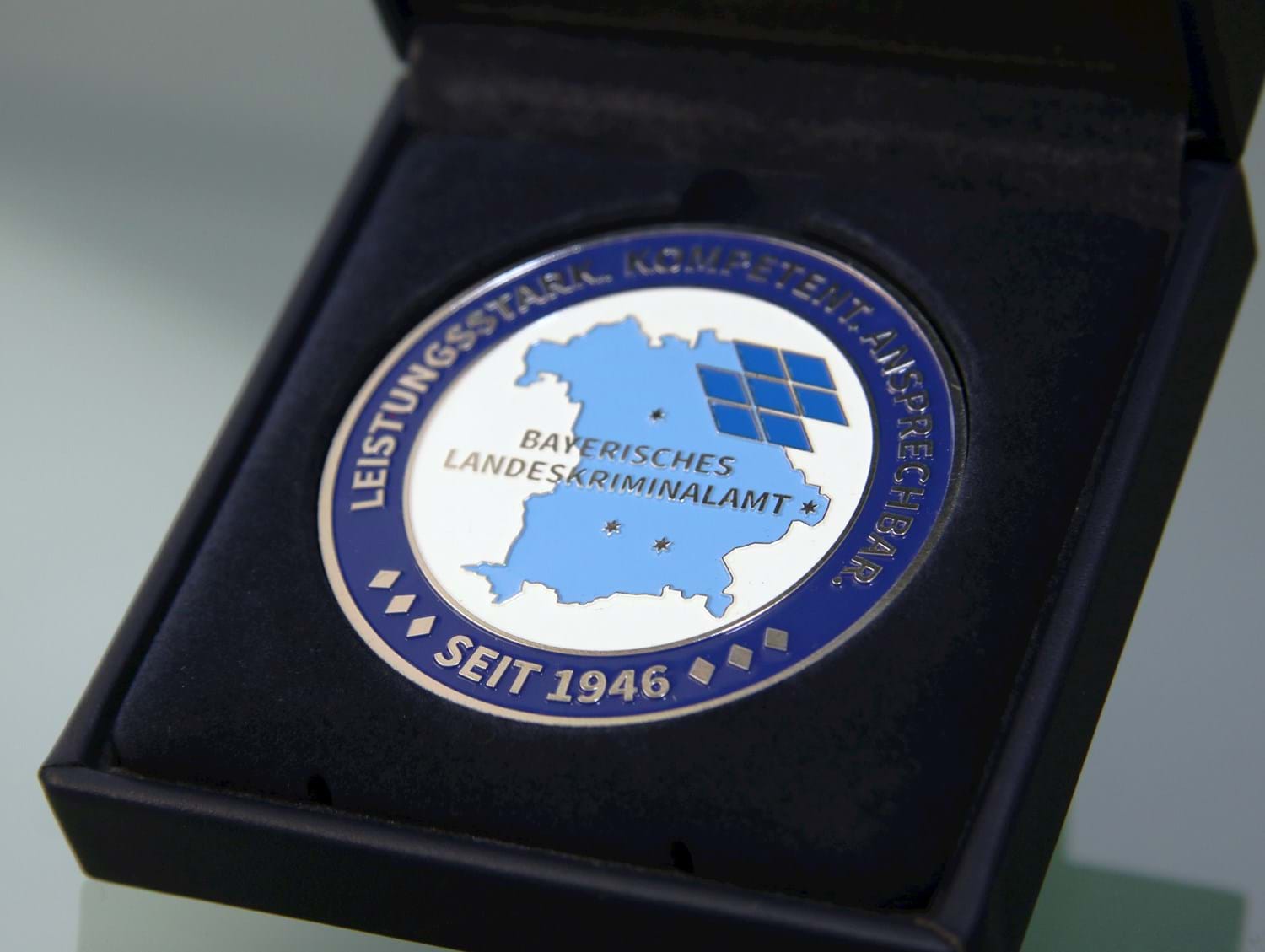 Eine Münze mit den auf einer Bayernkarte markierten Standorten des Landeskriminalamts überreichte LKA-Präsident Robert Heimberger an Landrat Franz Meyer.