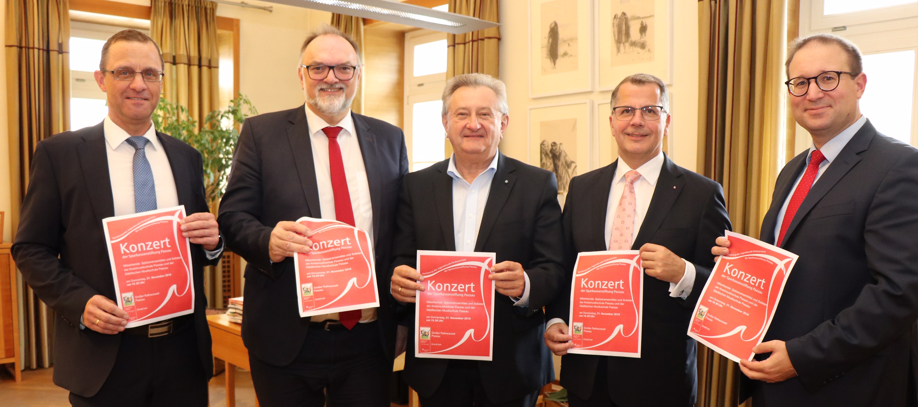 Rot auf Weiß für junge Musiker: Stiftungsgeschäftsleiter Armin Diewald (v.l.), OB Jürgen Dupper, Landrat Franz Meyer, Sparkassen-Vorstandsvorsitzender Christoph Helmschrott und Tobias Hofbauer (Pressesprecher Sparkasse Passau) präsentieren das traditionell rote Konzert-Plakat.